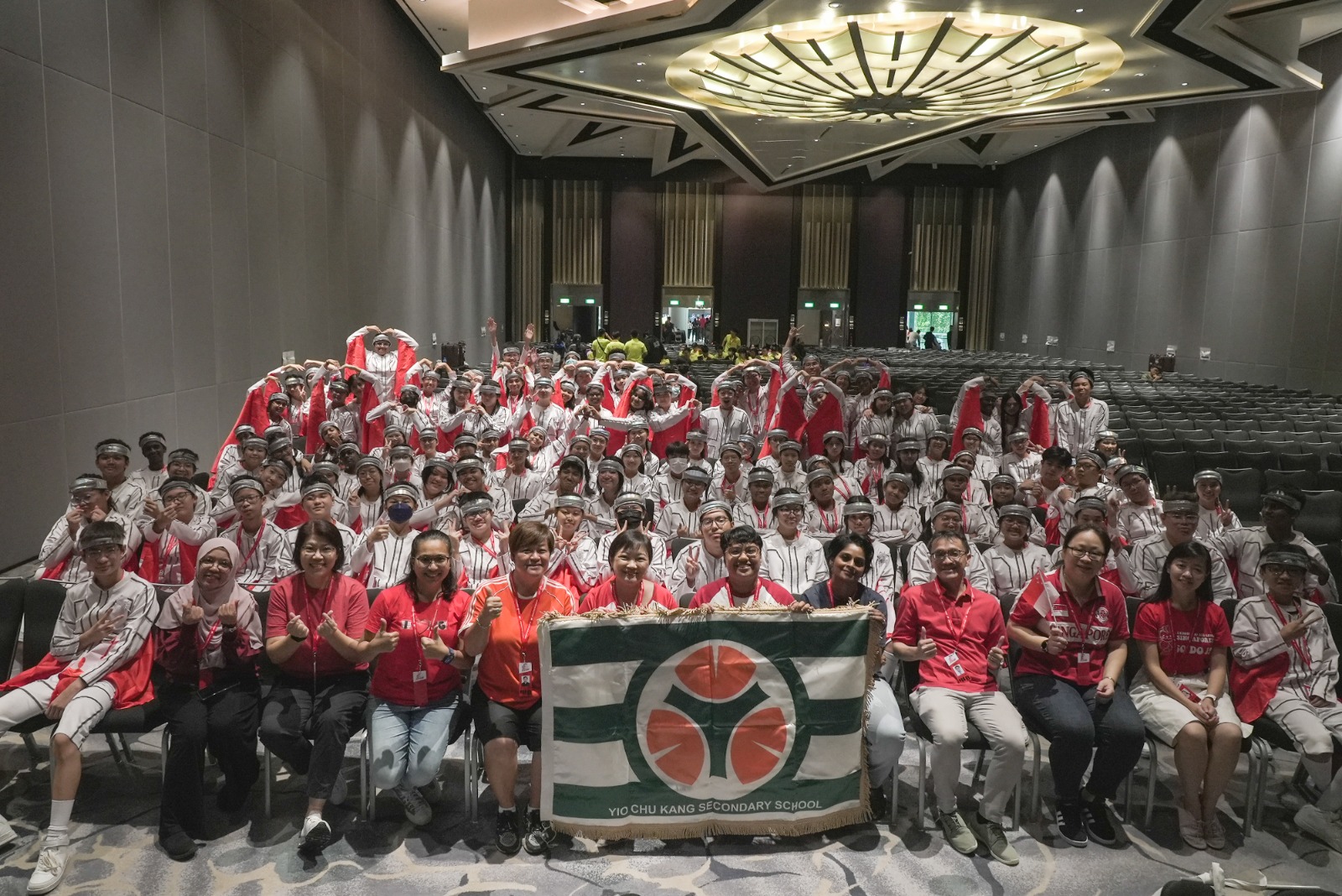 Group photo of students and teachers participating in NDP 2023 seated in a ballroom